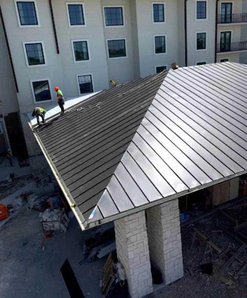 Crew installing standing seam metal roof panels on a commercial project in Perry